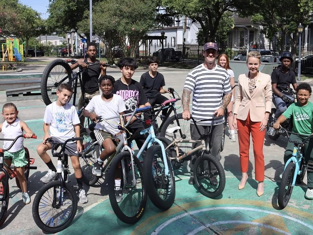 Young riders from a New Orleans youth bike program pose on BMX bikes with an X Games athlete and city leaders at a neighborhood park